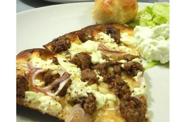 Pizza fatta in casa con agnello piccante e fresca insalata tzatziki